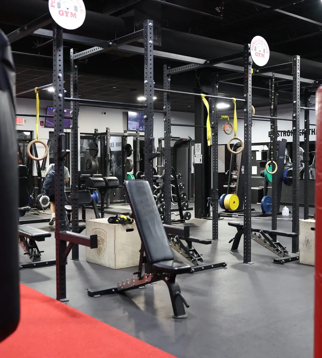 Strength-training area with squat racks, rings and an adjustable bench at Powerhouse Gym Brewster